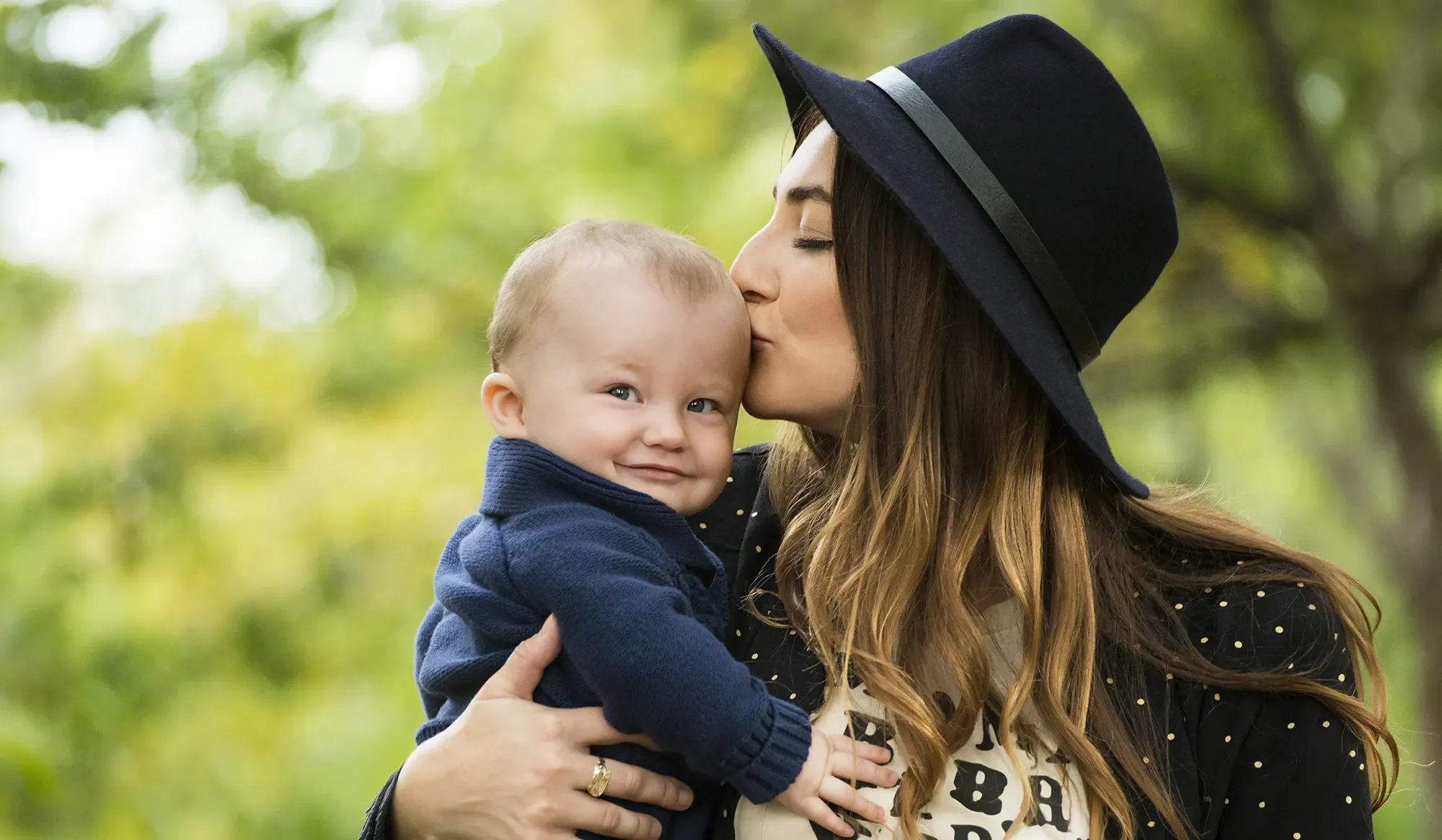 Portrait of a young mother kissing her baby son with love in a park in Winnetka IL.