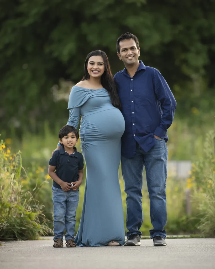 Standing Portrait of a pregnant young woman, her husband and toddler son in the park